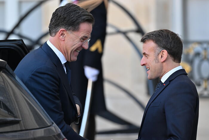 Two men in suits smiling and shaking hands at a formal event, capturing a moment unrelated to Donald Trump&rsquo;s Davos photo viral news.