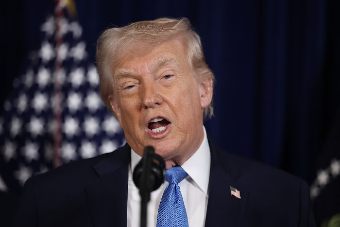 Donald Trump speaking at a podium with American flags in the background discussing civil rights protections.