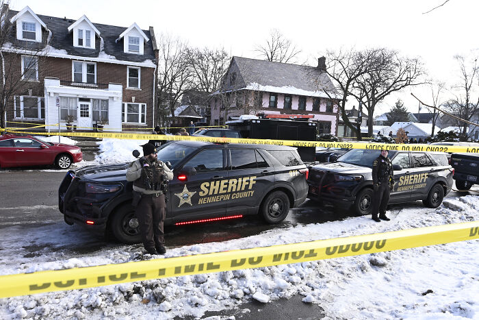 Police officers stand by sheriff vehicles at a crime scene with yellow tape investigating tragic fatal shooting involving ICE. Police officers stand by sheriff vehicles at a crime scene with yellow tape investigating tragic fatal shooting involving ICE.