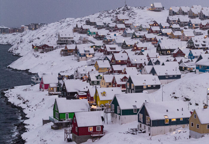 Snow-covered colorful houses in Greenland village, highlighting lawmakers' move to block Trump from invading NATO territory.
