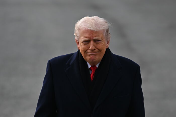 Former President Trump in a dark coat and red tie, addressing potential 200% wine tariffs amid international diplomatic tensions.