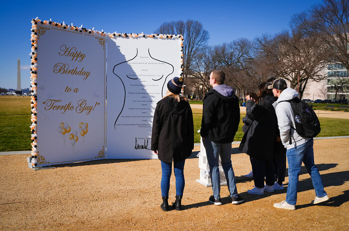 Visitors on the National Mall viewing an oversized replica of the alleged Trump&ndash;Epstein birthday note installation.
