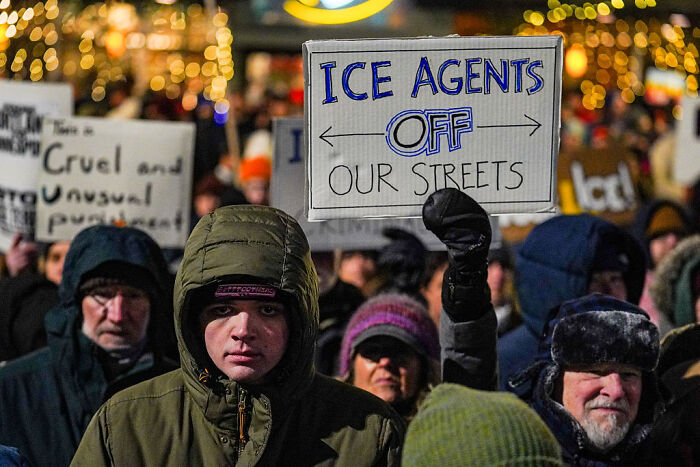Protesters holding signs against ICE agents during a nighttime rally, reflecting backlash on ICE deployment plans. Protesters holding signs against ICE agents during a nighttime rally, reflecting backlash on ICE deployment plans.
