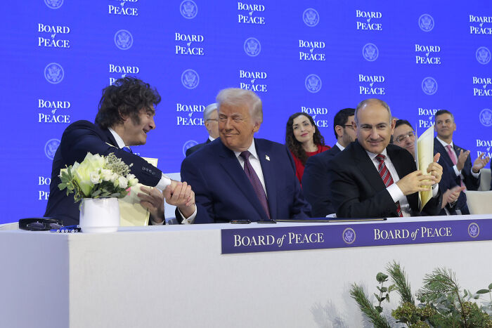 Donald Trump attempts power handshake at Davos event while attendees notice a pair of shoes in the background. Donald Trump attempts power handshake at Davos event while attendees notice a pair of shoes in the background.