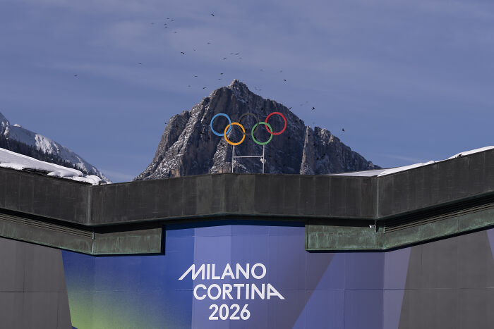 Olympic rings above Milano Cortina 2026 sign with mountain background, linked to Trump ICE deployment plan controversy. Olympic rings above Milano Cortina 2026 sign with mountain background, linked to Trump ICE deployment plan controversy.