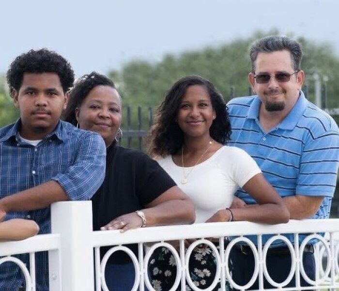 Family standing together outdoors by a white fence, representing the couple that adopted a 7-year-old daughter in Texas case. Family standing together outdoors by a white fence, representing the couple that adopted a 7-year-old daughter in Texas case.