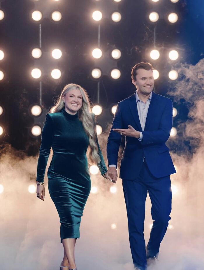 Erika Kirk and Charlie Kirk holding hands on a foggy stage with bright lights celebrating viral memorial sales.