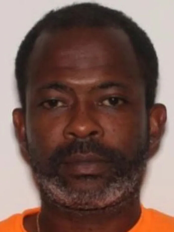 Mugshot of a man with a beard and mustache wearing an orange shirt related to child a***e case and homicide news.