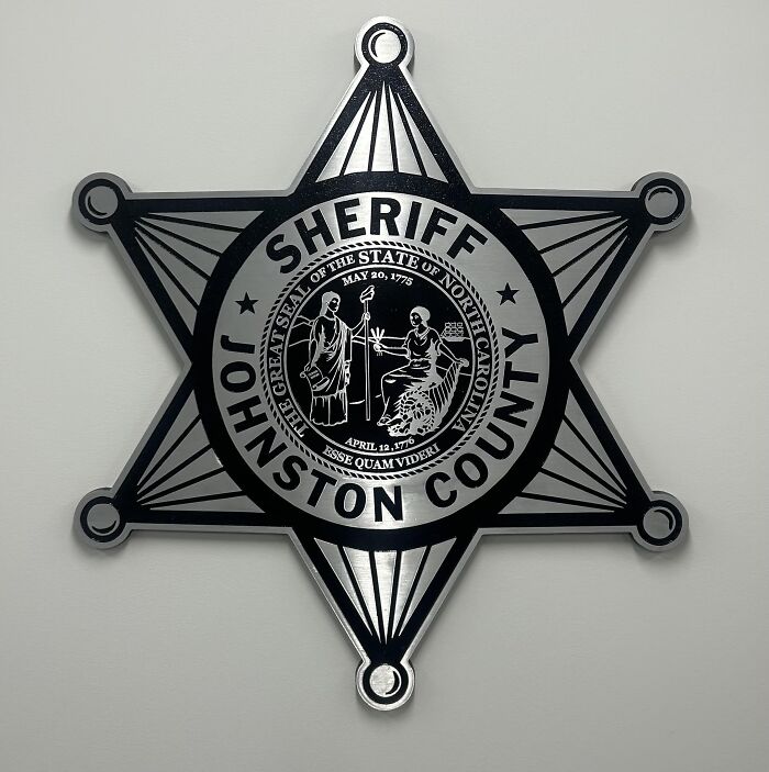 Johnston County Sheriff badge on wall, related to father allegedly hiding children&rsquo;s bodies case investigation.