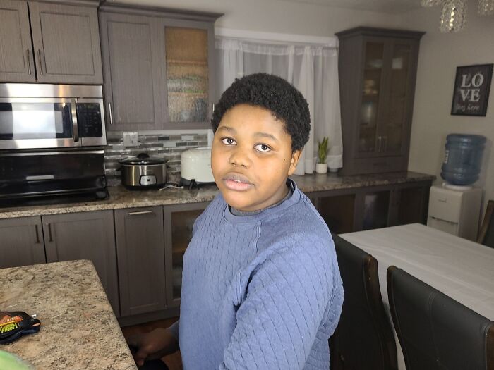 Young person sitting in a kitchen, representing families honoring children lost in Canada school attack after perpetrator identified.