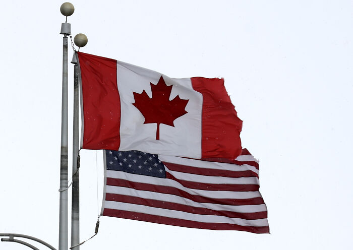 Canadian and American flags flying together representing bipartisan vote to cancel tariffs.