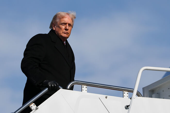 Donald Trump wearing black coat and gloves, boarding plane with Kennedy Center closure and repairs context. Donald Trump wearing black coat and gloves, boarding plane with Kennedy Center closure and repairs context.