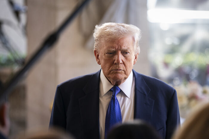 Former U.S. president in a suit and blue tie during an event focused on bipartisan vote on Canada tariffs.