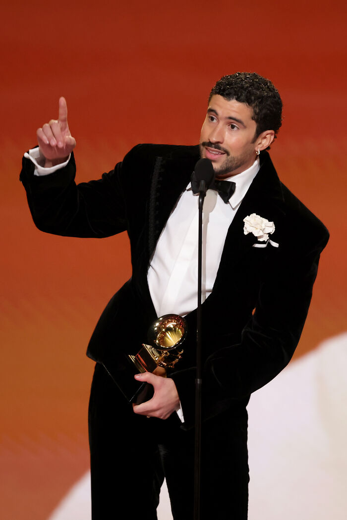 Male star at the Grammys holding an award and speaking out against ICE during acceptance speech on stage. Male star at the Grammys holding an award and speaking out against ICE during acceptance speech on stage.