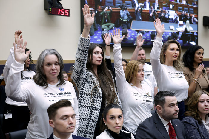 Group of people raising hands during a heated exchange involving Bondi and House Democrats in a congressional hearing room.