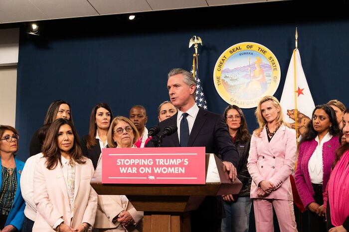 Jennifer Siebel Newsom speaking at podium with group, addressing media on war on women and stopping Trump&rsquo;s policies.