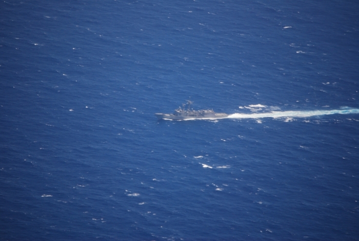 A U.S. Navy ship cutting through deep blue ocean waters, leaving a white wake, related to Iranian Oil Tanker incident.
